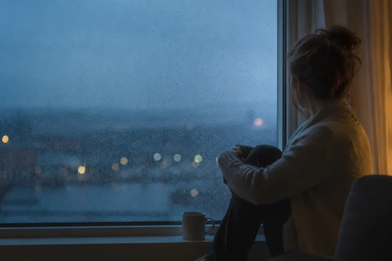 Person reflecting alone by a window, representing the emotional weight of self-destructive behavior